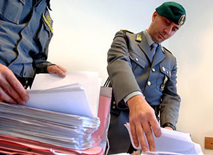 Ufficiali della Guardia di Finanza controllano documenti contabili durante un'ispezione.