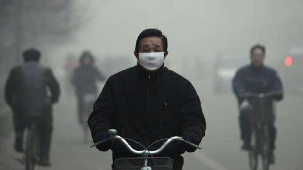 Cinese in bicicletta con la mascherina per evitare le polveri sottili dello smog.