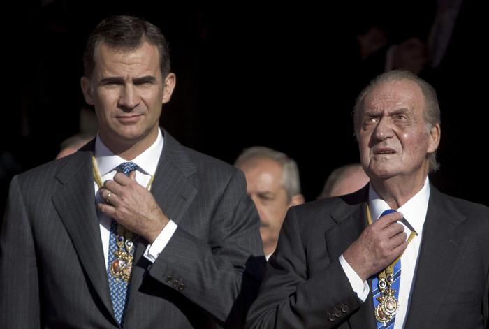 Il re emerito di Spagna Juan Carlos I (D) e suo figlio, l'attuale sovrano Felipe VI (S) si aggiustano la cravatta mentre aspettano per entrare in una sessione del Parlamento.
