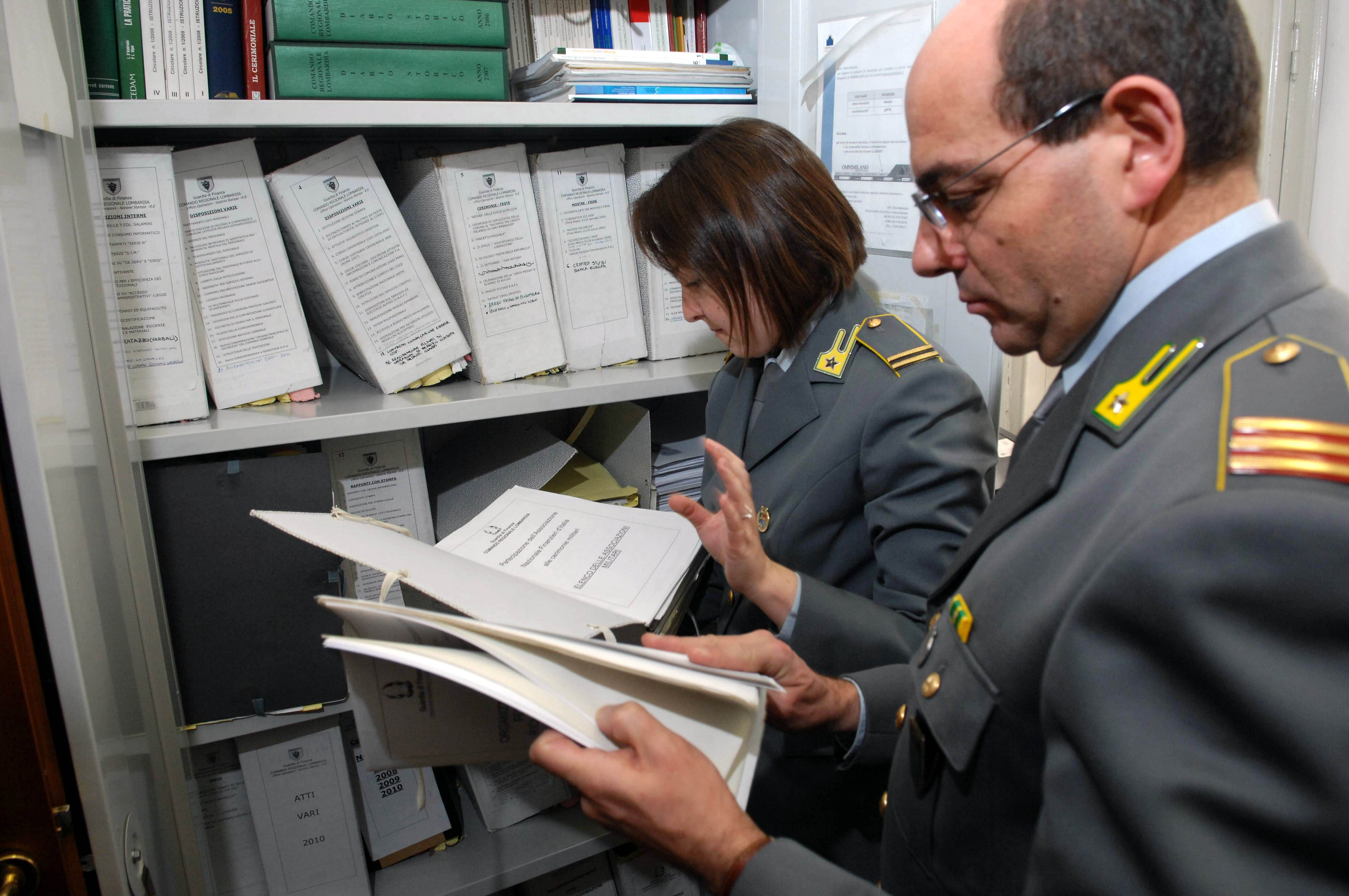 Agenti della Guardia diFinanza controllano faldoni e documenti d'archivio.