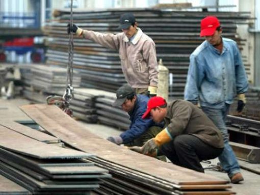 Lavoratori stranieri impegnati a sollevare delle lastre.