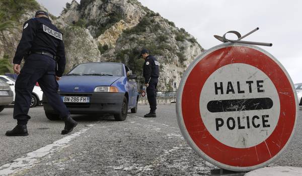 Poliziotti francesi controllano le auto che arrivano dall'Italia nella posto doganale di frontiera a Mentone.