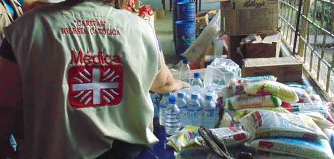 Volontari della Caritas distribuiscono bottiglie d'acqua ed alimenti.