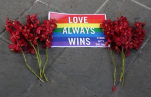 A sign and flowers lie on the ground outside the US Embassy during a vigil for those killed and wounded in the Sunday June 12, 2016 mass shooting at a gay nightclub in Orlando, Florida, in Bangkok, Thailand, Monday, June 13, 2016.  