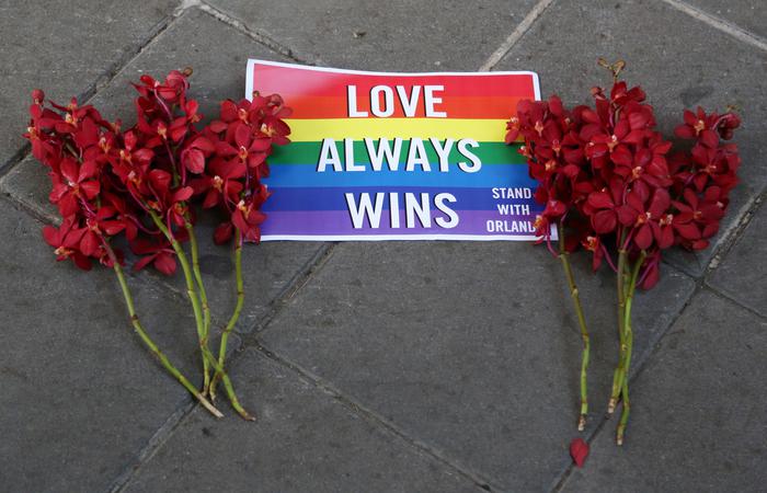 Un cartellone e fiori depositati sul marciapiedi davanti all'ambasciata Usa a Bangkok, Tailandi, in omaggio ai morti durante la sparatoria contro un nightclub gay in Orlando, Usa. Foto d'archivio.