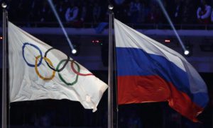 FILE- In this Feb. 23, 2014, file photo, the Russian national flag, right, flies after next to the Olympic flag during the closing ceremony of the 2014 Winter Olympics in Sochi, Russia.  (ANSA/AP Photo/Matthias Schrader, File) 