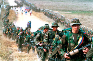 Leftist rebels of the Revolutionary Armed Forces of Colombia (FARC) patrol by a roadway near to San Vicente de Caguan, Caqueta province, Colombia, January 9. 1999. REUTERS/ Jose Miguel Gomez/File Photo - RTX2HPEB