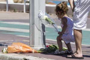 Una bambina, mentre depone una rosa sul lungomare Promenade des Anglais, dove è avvenuta la strage a Nizza,  15 luglio 2016. ANSA/MASSIMO PERCOSSI