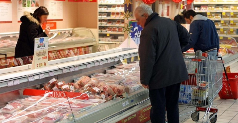 Un anziano guarda i prodotti in una macelleria.