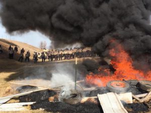 Tires burn as armed soldiers and law enforcement officers stand in formation on Thursday, Oct. 27, 2016, (Mike McCleary/The Bismarck Tribune via AP)