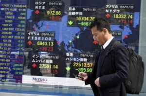A pedestrian walks past a stock market indicator board in Tokyo, Japan, EPA/FRANCK ROBICHON