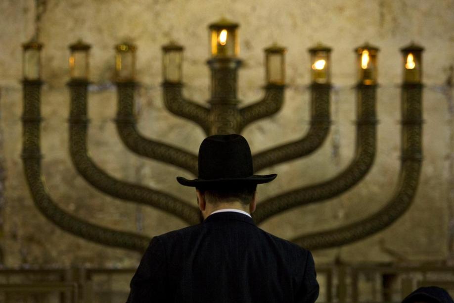 Un ebreo ortodosso pregando di fronte al candelabro Menorah.