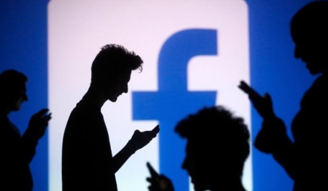 Ombre di persone guardando il proprio cellulare e sullo sfondo il logo di Facebook.