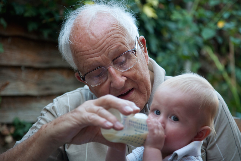 Nonno dà il biberon al nipote.