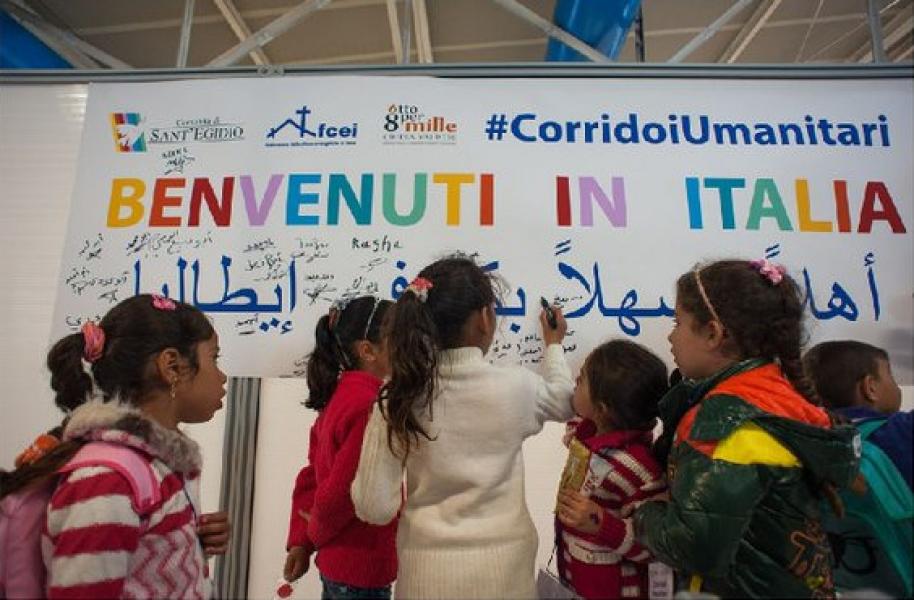 Arrivo a Roma dei profughi grazie ai corridoi umani, ricevuti con cartelloni di Benvenuti.