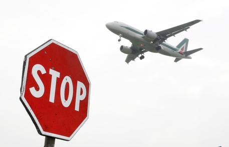 Un segnale di STOP e in lontananza un aereo Alitalia.