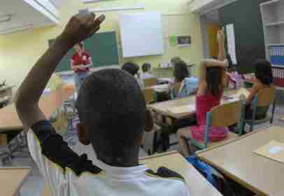 Scuola, un'aula delle elementari, un bambino africano con il braccio alzato.