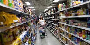 Una donna tra gli scaffali di un supermercato con il carrello della spesa