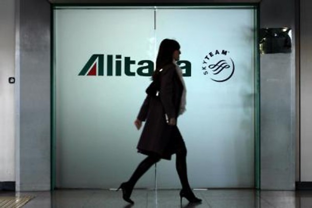 Alitalia, hostess di passaggio, con la scritta Alitalia sul fondo.