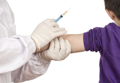 Dottoressa con siringa in mano tiene il braccio di un bambini per vaccinarlo