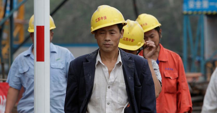 Operai cinesi con il casco protettivo giallo al lavoro