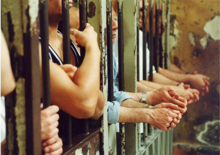 Carceri, dalle sbarre spuntano le braccia dei prigionieri.