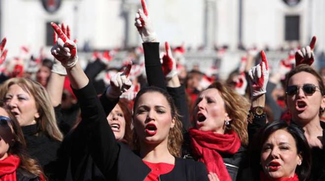 Dimostrazione di protesta di donne con fazzoletto rosso al collo contro l'aumento dei femminicidi.