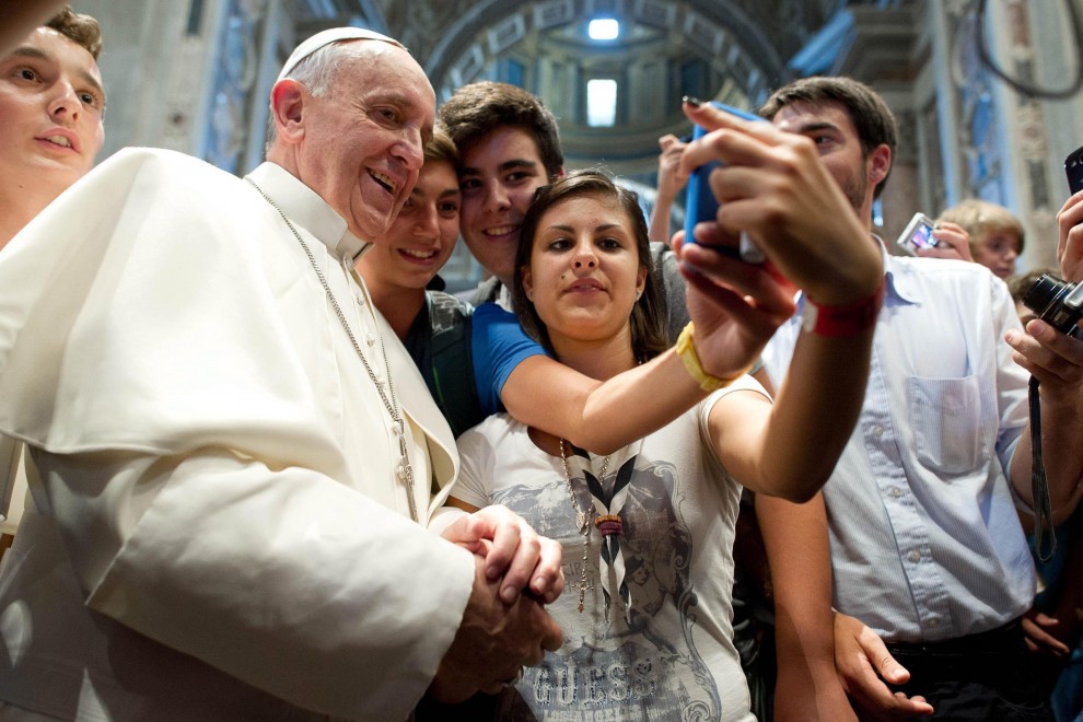 Papa Francesco con un gruppo di giovani facendo selfie col cellulare