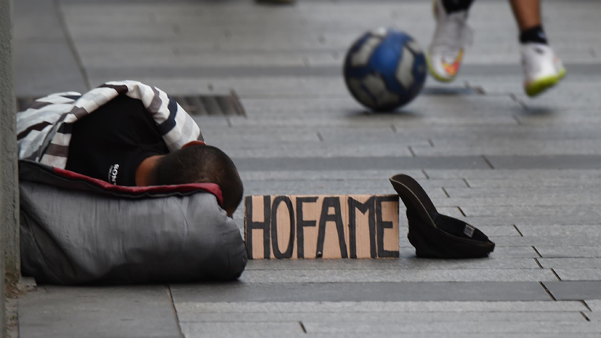 Povertà: persona stesa per terra con un cartello con la scritta "Ho fame"