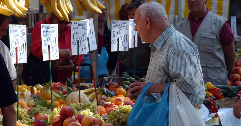 Una persona guarda la frutta e verdura esposta in un mercato.