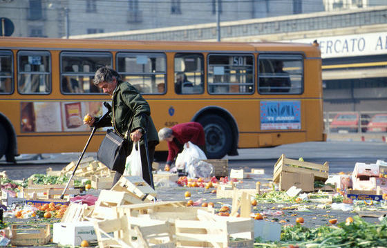 Un'anziana rovistando tra i rifiuti del mercato di frutta e verdure. Povertà