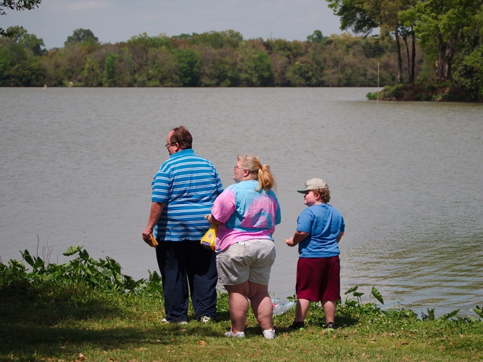 Una famiglia di persone sovrappeso in riva ad un lago. Obesi
