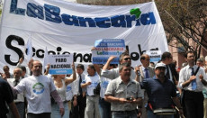Persone protestando in strada sollevando uno striscione con la scritta "Bancaria"