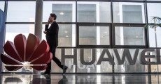 Un uomo camminando di fronte all'entrata di un negozio Huawei. hitech