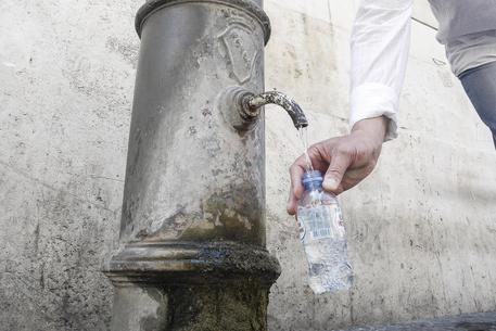 Un turista riempie d'acqua le sua bottiglietta da una fontanella pubblica in piazza del Pantheon