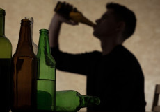 L'ombra di una persona bevendo da una bottiglia. Alcol