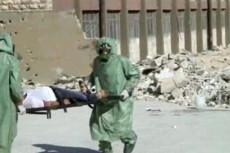 Infermieri in assetto anti chimico trasportano un ferito in barella. Assad