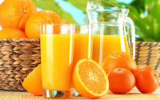 Una naranja cortada por la mitad, un vaso lleno de jugo de naranja y una jarra llena por la mitad