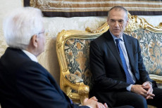 Il presidente Mattarella di spalle a sinistra e Cottarelli seduto sul divano mentre parlano