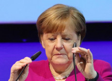 Angela Merkel aggiusta il microfono prima del suo intervento in conferenza stampa.