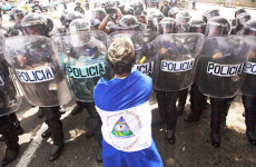 Un'immagine d'archivio delle proteste in Nicaragua: una ragazza avvolta dalla bandiera del Nicaragua affronta uno schieramento di polizia.