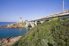 Un viadotto che sbocca su un promontorio costeggiando la riva del mare