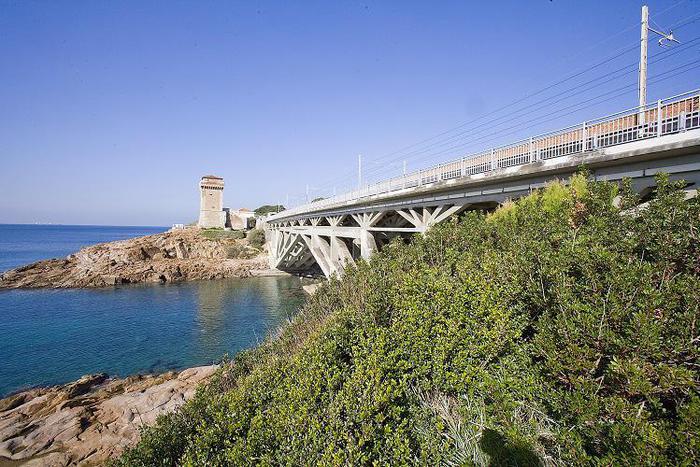 Un viadotto che sbocca su un promontorio costeggiando la riva del mare