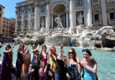 Turisti a Fontana di Trevi di spalle alla fontana mentre gettano le tradizionali monetine.