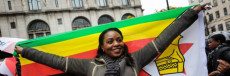 Ragazza dello Zimbabwe con le braccia stende la bandiera nazionale.