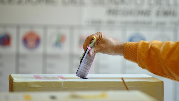 Una mano deposita la scheda elettorale nell'urna.