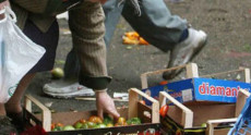 Povertà: Le mani di una persona raccolgono della verdura da una cassetta abbandonato per terra