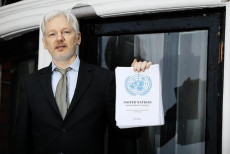 In una foto d'archivio Assange mostra i documenti trafugati.