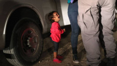 Una bambina piange appoggiata ad un Suv, a lato le gambe della mamma e del poliziotto.