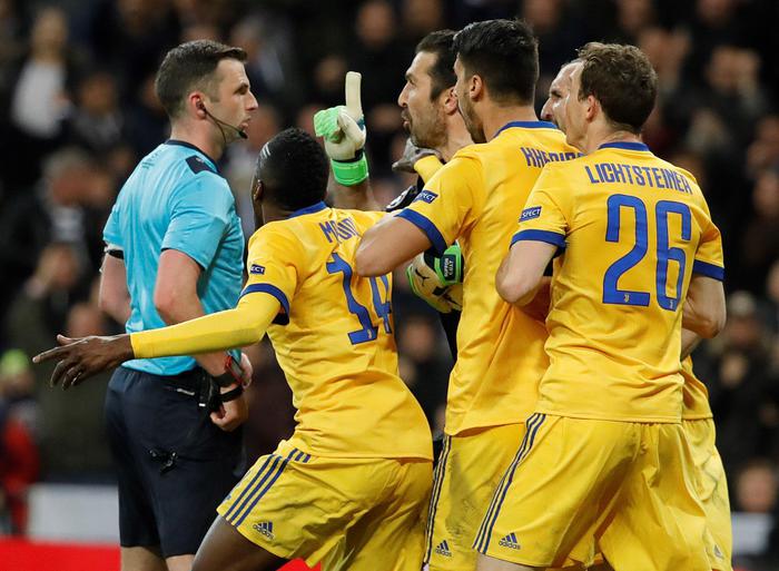 Buffon, circondato da altri giocatori della Juventus, protesta contro l'arbitro.